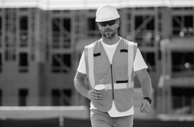 Kasklı inşaat işçisi dışarıda çalışıyor. Amerikan ahşap bina inşaatında kahve molasında miğferli bir inşaatçı.