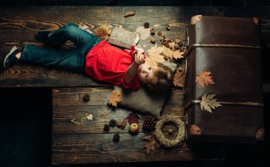 Sonbahar sonbahar yaprakları arka plan üzerinde yaprakları ile oynayan sevimli küçük çocuk. Leaf fall ile eğleniyor çocuk. Altın yaprak ile mevsimlik giysiler içindeki çocuk. Sonbahar konsepti