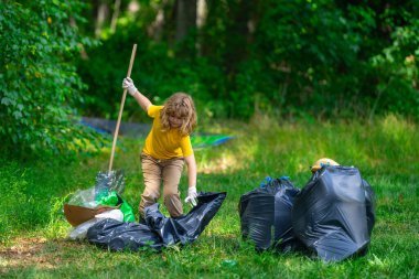 Küresel çevre kirliliği. Çocuk dışarıda plastik çöp topluyor. Çevre koruma kavramı. Çocuk çöp torbasına atık koyuyor. Eko çocuklar gönüllü. Çevre kirliliği
