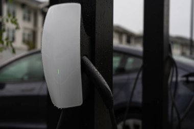 EV istasyonunda elektrikli akü şarjı. EV araba ve ev şarj istasyonu kavramı. Elektrikli araba şarj oluyor. Şarj kablosu olan elektrikli bir araba. Yükleme noktası