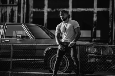 Yakışıklı hippi İspanyol modelin portresi. Sokaktaki seksi, modern adam. Moda erkeği sokak arka planında poz veriyor. Adam sokak çetesi, sosyal sorun. Suç şehri. Tehlikeli Amerikan Bölgesi