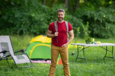 Adam doğada kamp yapmayı seviyor. Kamp gezisi. Yürüyüşten sonra bir çadırda dinleniyor. Huzurlu bir kamp alanında tatil. Yazın piknik. Açık hava macerasının özgürlüğü. Erkek kampı ve rahatlama