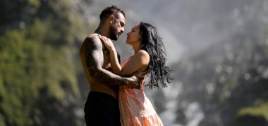 Şelalenin yanında öpüşen romantik bir çift. Tutkulu çift yaz doğasına karşı sarılıyor. Kırsalda romantik aşıklar. Aşık seksi çiftin romantik portresi inanılmaz manzarada sarılıyor.