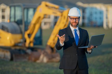 İnşaat işletmecisi ya da şantiye müdürü. İnşaat müdürünün portresi, kazıcının yanında şapka ve takım elbise giymiş. İnşaat yöneticisi veya denetçisi ile yenileme