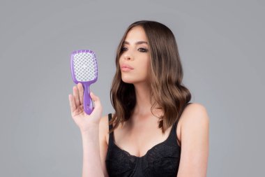 Çekici esmer saçlı kadının portresi saç fırçasıyla saçını tarıyor, izole edilmiş. Genç, güzel bir kadın uzun, sağlıklı, esmer saçları, klasik saç stili, restorasyon maskesi, saç bakım konsepti.