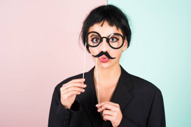 Siyah peruklu genç bir kadın sahte bıyığı pozitif ve mutlu yapıyor. Komik kız gülüşü. Genç transseksüel kadın. Komik kadın suratı. Çekici, suratını buruşturan komik kızın portresi. Duygu kızı.