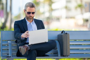 Kendine güveni tam bir iş adamı. Yaz parkında dizüstü bilgisayar ve telefonla bankta oturuyor. Başarı uzaktan yapılan bir iş. Orta yaşlı iş adamı tatilin tadını çıkarıyor. İş adamı bir bankta mola veriyor.