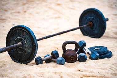 Halter spor ekipmanları. Spor geçmişi. Yaz sporu için kumda halter. Kum arka planda halter. Spor salonunda halterle idman yapıyorum. Spor afişi