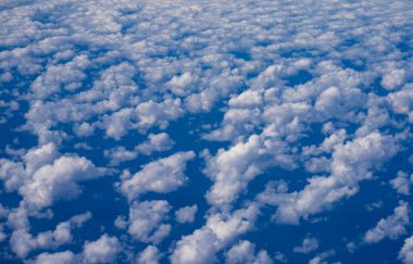 Kabarık bulutlu arka planlı mavi gökyüzü. Parlak mavi gökyüzü arkaplanı. Bulutlu beyaz bulutlar. Güneşli bir günde sakin bir gökyüzü. Bulutların arasından geçen güneş ışığı. Yumuşak bulutlu bahar gökyüzü