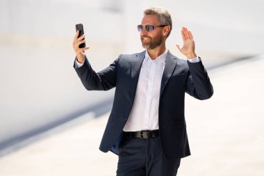 İş portresi. Dışarıda telefonu kullanan mutlu bir iş adamı. Başarılı bir lider. Takım elbiseli bir adam dışarıda telefonla konuşuyor. İş adamı telefonu tut. Telefon kullanan bir iş adamı. İnternet üzerinden iş toplantısı