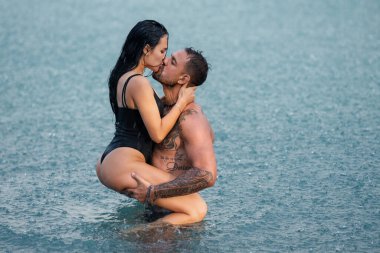 Romantik aşıklar suda öpüşürler. Şefkatli aşıklar dışarıda öpüşüyor. Yaz öpücüğü. Çift yağmurda öpüştü. Şehvetli çift yağmurun altında öpüşüyor. Seksi öpüşen çift. Romantik çift öpüşüyor.