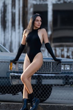 Retro arabanın yanında kadın model. Şehvetli kadın garajda seksi poz veriyor. Güzel kız cinsellik yayar. Lüks Amerikan güzeli sokaklarda. Vücut kıyafetli ve çizmeli seksi bir kadın. Seksi poz. Uzun Bacaklar
