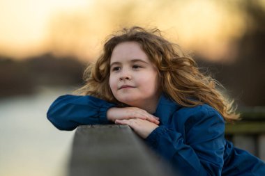 Hayalperest küçük. Rahatlamış çocuk parkta esintiyi hissediyor. Çocuk yüzünde düşünceli bir ifade. Geleceğin düşünürü sakin bir günün tadını çıkarıyor. Huzurlu bir çocuğun portresi. Hayal gücünü keşfeden sevimli çocuk.