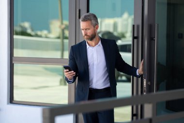 İş adamı bir ofis binasına giriyor. Yetişkin bir iş adamı toplantıya giriyor. İş adamı ofis kapısından içeri giriyor. Karizmatik iş adamı kapıdan giriyor. İş anlaşması