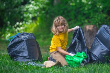 Çocuk dışarıda çöp topluyor. Ekoloji konsepti. Çevre kirliliği. Dünya Günü. Çöp tenekelerini geri dönüşümle temizleyin. Doğa temizliği. Çevre plastik kirliliği