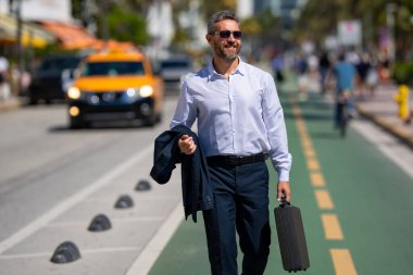 İş adamı işe yürüyerek gider. Hispanik iş adamı sokakta güven içinde yürüyor. Ofis çalışanı ofise gidiyor. Olgun bir iş adamı şehirde yürüyor. Dışarıda dolaşan gömlekli bir iş adamı.