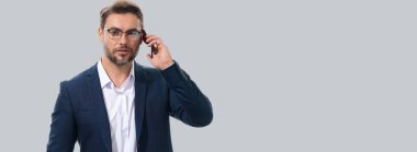 Takım elbiseli bir iş adamı telefonda konuşuyor. Promosyon mobil uygulaması. Stüdyonun arka planında izole edilmiş akıllı telefon kullanan sıradan giyinmiş bir iş adamı. Başlık için afiş, kopyalama alanı. Web tasarımı için poster