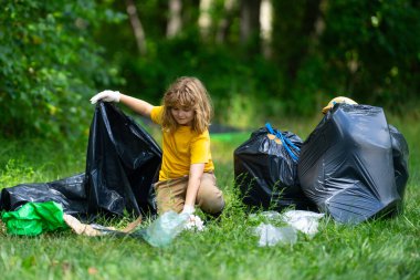 Çocuk doğayı temizlemek için plastik çöp topluyor. Çocuk dışarıdaki çöpleri temizliyor. Ekoloji konsepti. Çevre Günü. Dünyayı kurtar. Çöp geri dönüşüm çöpü. Ekoloji. Çevresel bakım. Eko çocuk