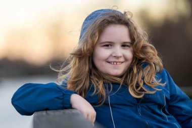 Bir çocuğun gözlerinde huzur ve ilham. Masumiyet ve mucize bir portrede yakalanır. Küçük hayalperest portresi. Açık havada çocukluk anı. Sarışın çocuk dışarıda huzurlu bir anın tadını çıkarıyor.