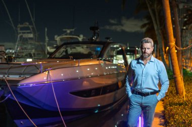 Yatın yanındaki zengin adam. Zengin milyoner adam lüks yaşam tarzının tadını çıkarıyor. Özel bir yatta milyoner bir adam. Finansal özgürlük. Milyoner bir iş adamıyla pahalı bir yat.