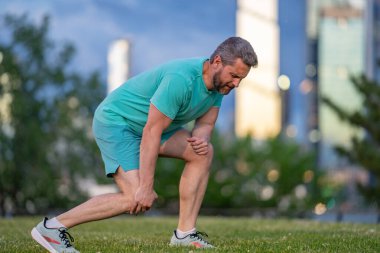 Dizler üstüne dizler. Diz ağrısı çeken atletik bir adam. Bacağını tutan yaralı bir adam. Koştuktan sonra acı. Dizinden yaralanan bir adam. Antrenman bacak ağrısı. Koşu diz travmasına yol açıyor.