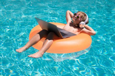 Serbest çalışma, uzaklık, online çalışma, e-öğrenme. Havuzda rahatlayan, yaz suyunda dizüstü bilgisayar kullanan komik bir iş adamı. Çocuk çevrimiçi tropikal deniz üzerinde çalışıyor