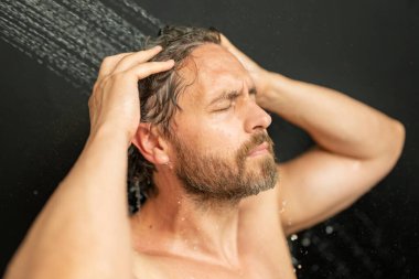 Adam banyoda saç yıkıyor. Küvette banyo yapan adam. Yüzü duşta köpüklü. Banyo yapan adam duş alıyor. Duş alan adamı kapatın. Duş konsepti. İnsan duşta su altındadır.