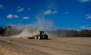 Traktör tarlayı sürüyor. Kırsalda sonbahar çiftçiliği. Kırsal tarım arazilerinde traktör. Toprakta çalışan tarım makinesi ya da traktör. Çekici tarla sürme çiftliği. Çiftlik arazisi
