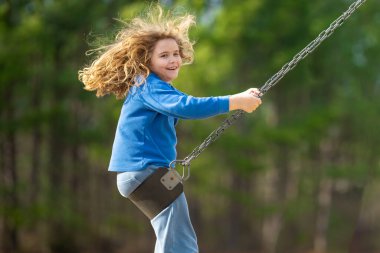 Heyecanlı çocuk eğleniyor. Çocuk bahçesinde mutlu bir çocuk. Havada sallanan kaygısız çocuk. Mutlu çocuklar dışarıda oynuyor. Sarışın çocuk heyecandan titriyor. Dışarıdaki oyuncu çocuk. Komik çocuk suratı