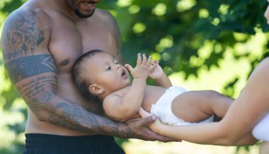 Mutlu genç aile, farklı ebeveynler yaz bahçesinde bebekle eğleniyor. Dışarıda küçük bir çocuğu olan çok ırklı bir aile. Karışık ırk ailesi. Doğada çocuğu olan çok ırklı bir aile.