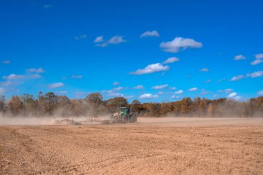 Traktör tarlayı sürüyor. Kırsalda sonbahar çiftçiliği. Kırsal tarım arazilerinde traktör. Toprakta çalışan tarım makinesi ya da traktör. Çekici tarla sürme çiftliği. Çiftlik arazisi