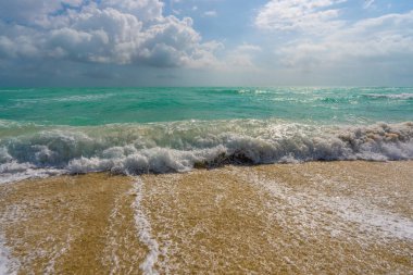 Deniz kıyısı. Renkli deniz kıyısı suyu. Sıcak okyanus esintisi. Yaz sahili. Deniz arka planı. Mavi okyanus. Kumsal. Okyanus dalgaları. Yaz mevsimi. Tropik sahil şeridi. Köpüklü dalga sıçraması