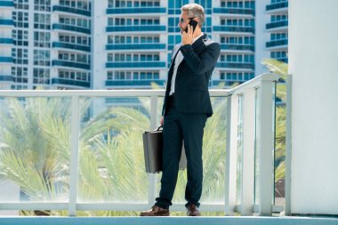 Telefonu olan olgun bir iş adamı. Finans uzmanı telefonda önemli bir arama yapıyor. Profesyonel şirket dışarıda telefonla konuşuyor. İş yöneticisi telefon mesajlarını kontrol ediyor