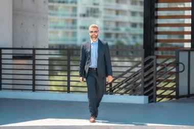 Başarılı bir iş adamı dışarıda dizüstü bilgisayarla dolaşır. Kendine güvenen iş adamı dizüstü bilgisayarı dışarıda tutuyor. Takım elbiseli, olgun, serbest çalışan bir iş adamı. Finans işi. Takım elbiseli zengin iş adamı