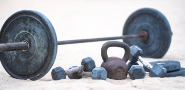 Kettlebell ve ağırlık arka planı. Ağır ağırlıklarla vücut geliştirme. Dambıllarla park egzersizi. Ağırlıklarla spor sahnesi. Kettlebell, halterler ve halterler. Ağırlık çalışması.