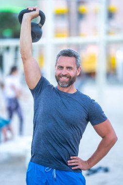 Kettlebell dışarıda çalışıyor. Atletik adam kettlebell kaldırıyor. Kettlebell 'le antrenman yapan zinde bir adam. Gömleksiz sporcu kettlebell egzersizleri yapıyor. Olgun adam dışarıda antrenman yapıyor. Açık havada antrenman yapmak