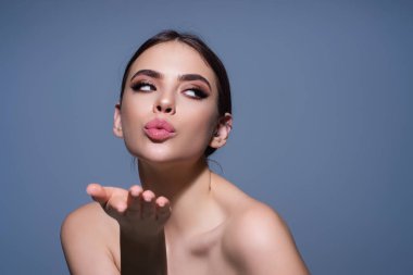 Stüdyonun arka planında izole edilmiş güzel bir kızın öpüştüğü portre. Güzel bir kadın hava öpücüğü yolluyor. Güzel kız hava öpücüğünü kameraya yansıtıyor, aşkını ifade ediyor. Şefkat ve hoş duygular