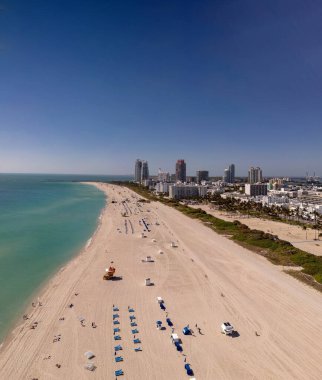 Miami 'de kumsalda güneşli yataklı, okyanus dalgalı bir plaj. Muhteşem manzaralı Miami Beach cenneti. Güney Sahili Miami cankurtaranı. Miami 'de huzurlu bir deniz kenarı inzivası. Kıyı gevşemesi