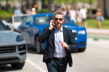 Toplantıya koşan zengin bir işadamı. İşadamı yolda koşar. Takım elbiseli bir iş adamı işe koşuyor. İş adamı dışarı atlar. İş adamı teslim tarihine yetişmeye çalışıyor. İşadamı acele et.