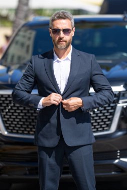 Lüks bir arabanın yanında zengin bir işadamı. Zengin bir iş adamı. Zarif zengin iş adamı. Pahalı arabası olan bir patron. Premium arabada duran zengin bir iş adamı. İş başarısı. Zenginlik kavramı