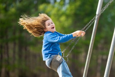 Çocuk salıncakta eğleniyor. Çocuk bahçesinde mutlu bir çocuk. Havada sallanan kaygısız çocuk. Mutlu çocuklar dışarıda oynuyor. Sarışın çocuk heyecandan titriyor. Dışarıdaki oyuncu çocuk. Komik çocuk suratı