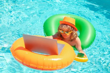 Havuz başında dizüstü bilgisayarda çalışan bir çocuk. Yaz çevrimiçi teknoloji. Yaz tatilinde tropik deniz sahillerinde dinlenen bir gezgin. Dışarıda bilardoda dizüstü bilgisayarla çalış