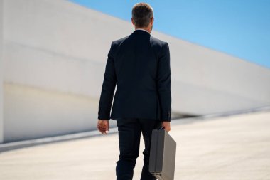 İş adamı tekrar dışarı çıkıyor. Takım elbiseli başarılı bir iş adamı. Kendine güveni tam bir iş adamı. İşadamı çekip gidiyor. Takım elbiseli zengin adam. Çantası olan şehirli iş adamı.