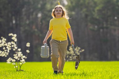 Bahçede ağaç yetiştiren bir çocuk. Çocuk kürekle toprak kazıyor ve ağaç dikiyor. Çocuk bahçıvan meyve ağaçları yetiştiriyor. Çocuklarla ağaç yetiştirmek. Çocuklar için bahçe işleri. Kürekli çocuk ağaç yetiştiriyor.