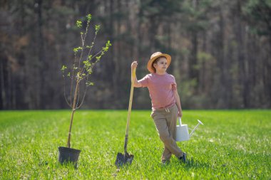Çocuk arka bahçeye ağaç dikiyor. Bahar tarlasında çocuk dikme ağacı. Sulama kovası ve kürekle ekmek. Bahçe çiftliğinde ağaç yetiştiren çocuk. Çocuk işi