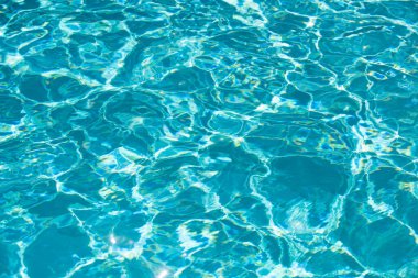 Mavi havuz suyu arka planı. Bulanık şeffaf, durgun su yüzeyi dokusu. Güneş ışığı altında su dalgaları kopyalama alanı ile
