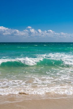 Turkuaz deniz dalgası hareketi. Yaz plajı. Sakin deniz. Lüks sahil beldesi. Parlak gökyüzü ve sahilde dalgalar. Güzel köpüklü kıyı şeridi. Deniz arka planı. Mavi okyanus. Kumlu okyanus plajı. Deniz dalgaları