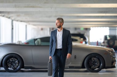 Zengin bir iş adamı pahalı lüks bir arabada. Takım elbiseli zengin bir iş adamı. Şehirdeki başarılı zengin iş adamı. Kendine güvenen bir iş adamı. Başarı işi. İş adamı sokakta yürüyor