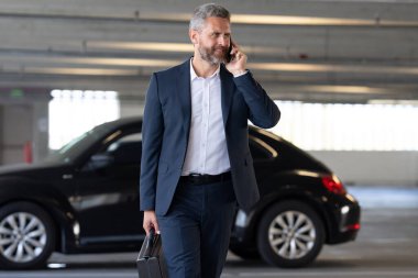 Zengin bir iş adamı. Zengin işadamı başarısının tadını çıkarıyor. Şık takım elbiseli lüks iş adamı. Pahalı arabanın önündeki zengin adam. Lüks iş seyahati. Kendine güveni olan zengin bir iş adamı