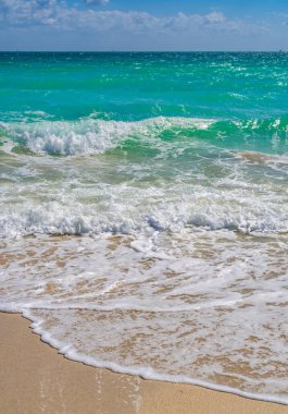 Deniz arka planı. Mavi okyanus. Kumlu okyanus plajı. Okyanus dalgaları. Yaz mevsimi. Tropik okyanus kıyısı. Egzotik turkuaz su. Köpüklü dalga denize sıçrıyor. Güneşli sahil manzarası